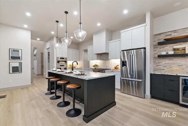 3359 E Warm Springs Ave, Boise, ID 83716 - kitchen featuring stainless steel appliances, modern cabinets, decorative backsplash, white cabinetry, and light wood-style flooring
