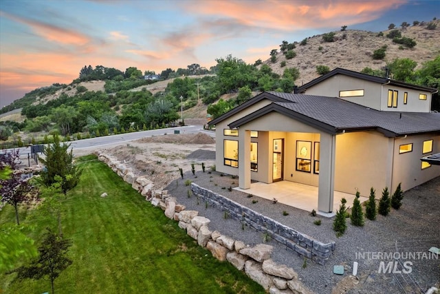 3359 E Warm Springs Ave, Boise, ID 83716 - back of house featuring stucco siding, a patio, a yard, and a mountain view