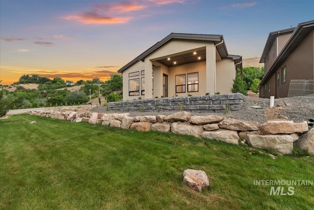 3359 E Warm Springs Ave, Boise, ID 83716 - back of property at dusk featuring stucco siding and a yard