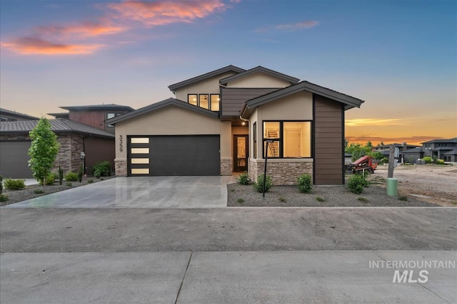 3359 E Warm Springs Ave, Boise, ID 83716 - modern home with stone siding, an attached garage, concrete driveway, and stucco siding