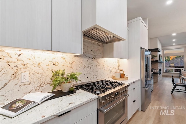 3359 E Warm Springs Ave, Boise, ID 83716 - kitchen featuring premium appliances, modern cabinets, light wood-style floors, white cabinetry, and light stone countertops