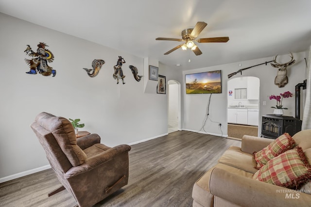 420 E 3rd St, Shoshone, ID 83352 - living area with a ceiling fan, wood finished floors, baseboards, and a wood stove