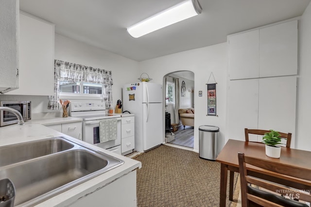 420 E 3rd St, Shoshone, ID 83352 - kitchen with white appliances, a sink, carpet, and white cabinetry
