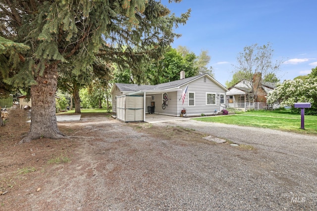 420 E 3rd St, Shoshone, ID 83352 - view of front facade with dirt driveway, a front lawn, a chimney, and a carport