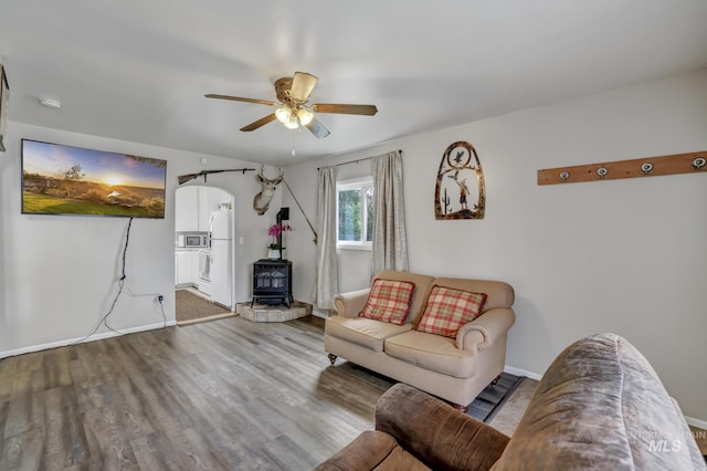 420 E 3rd St, Shoshone, ID 83352 - living room with a wood stove, ceiling fan, wood finished floors, baseboards, and arched walkways