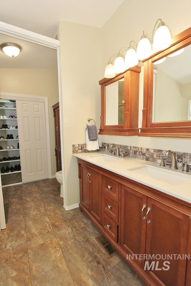 full bathroom featuring visible vents, a sink, double vanity, and toilet