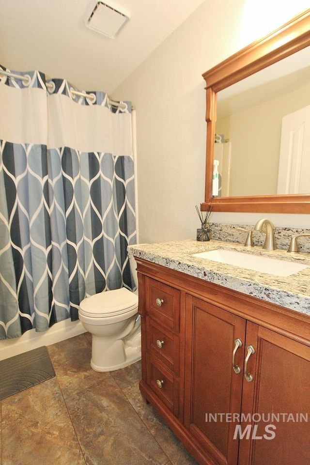 bathroom with toilet, visible vents, stone finish floor, and vanity