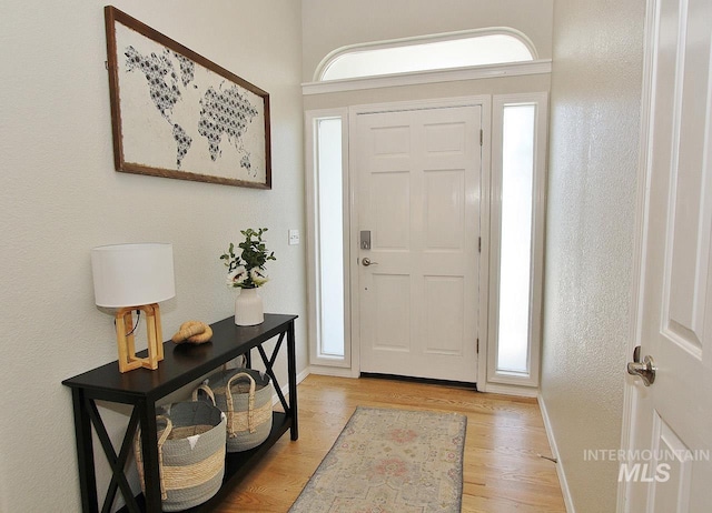 entryway featuring baseboards, light wood finished floors, and a wealth of natural light