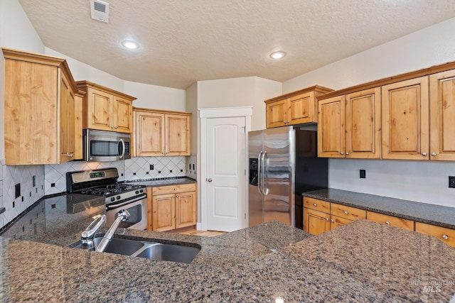 3993 N Heritage View Ave, Meridian, ID 83646 - kitchen featuring stainless steel appliances, a sink, a textured ceiling, tasteful backsplash, and dark stone countertops