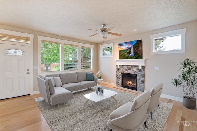 3993 N Heritage View Ave, Meridian, ID 83646 - living room featuring a textured ceiling, baseboards, a fireplace, ceiling fan, and light wood finished floors