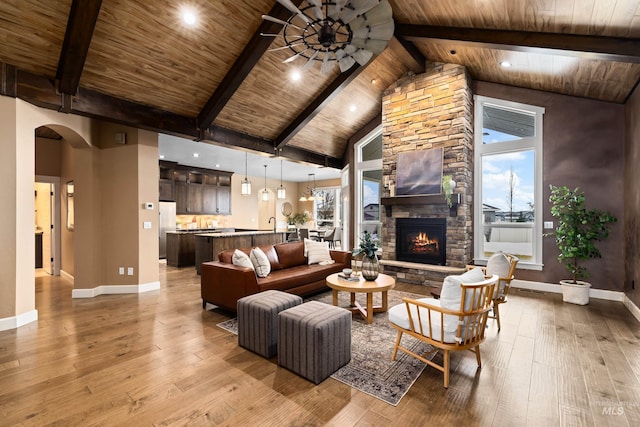 living room featuring a stone fireplace, wooden ceiling, beamed ceiling, and light wood-style flooring