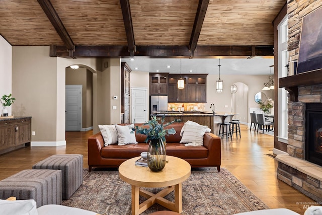 living room featuring wooden ceiling, a fireplace, arched walkways, and wood finished floors