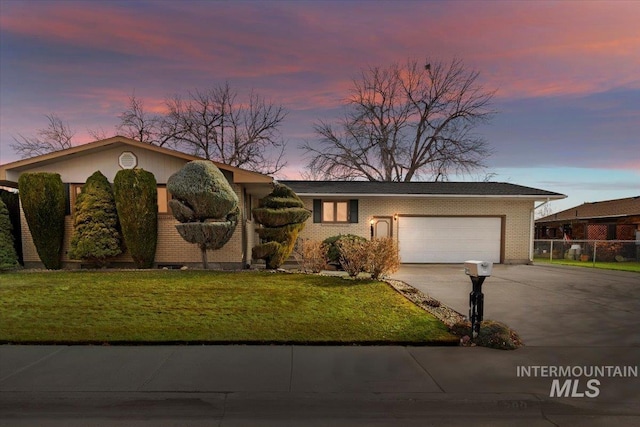 view of front facade with fence, driveway, an attached garage, a lawn, and brick siding