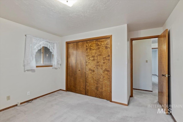 unfurnished bedroom featuring carpet, baseboards, a closet, and a textured ceiling