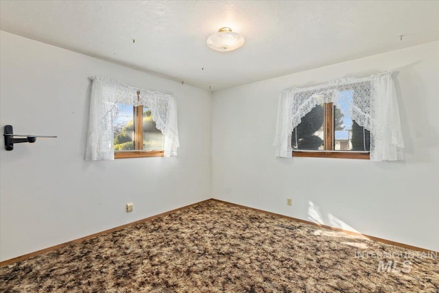 carpeted spare room featuring baseboards