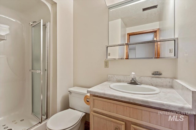 full bathroom with vanity, toilet, visible vents, and a stall shower