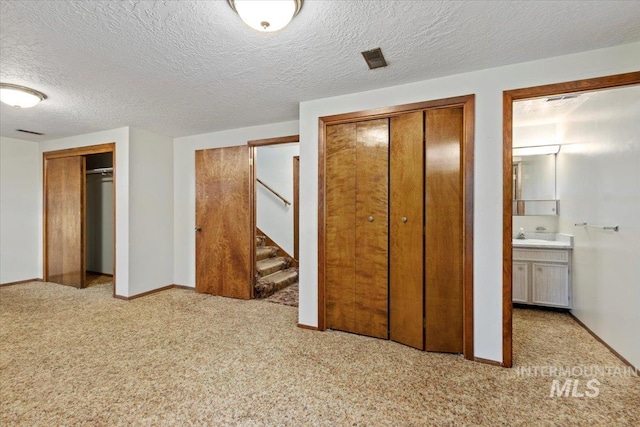 unfurnished bedroom featuring baseboards, multiple closets, and carpet floors