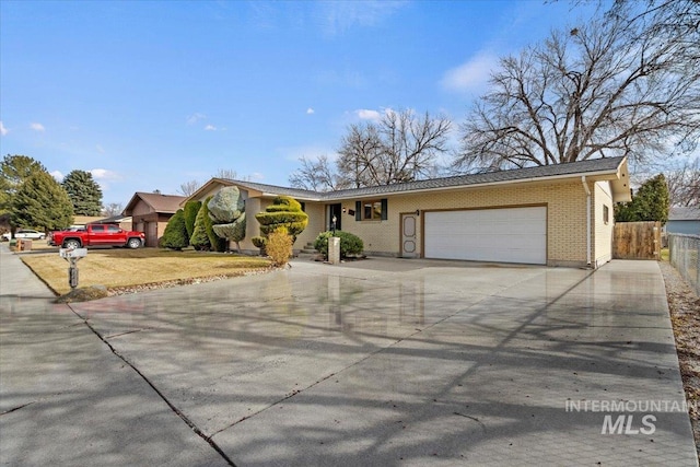 single story home with an attached garage, fence, brick siding, and driveway