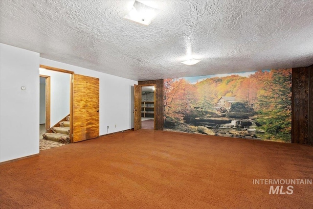 unfurnished room with stairway, carpet floors, and a textured ceiling