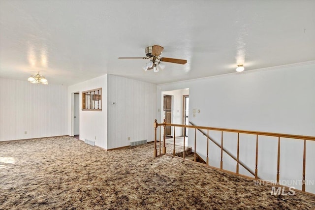 spare room with visible vents, ceiling fan with notable chandelier, and carpet