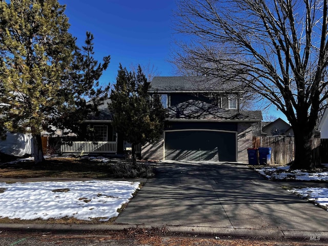 traditional home featuring concrete driveway, covered porch, fence, and an attached garage