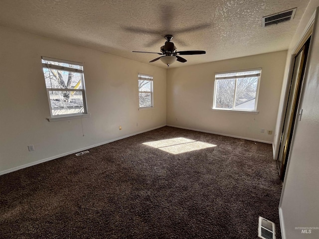 carpeted spare room with a textured ceiling, visible vents, and baseboards