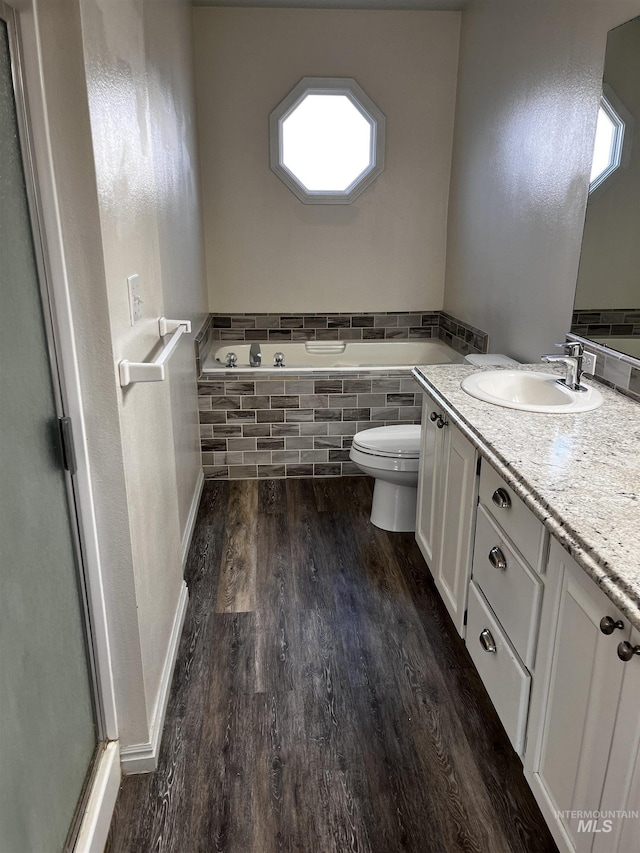 bathroom featuring toilet, a healthy amount of sunlight, wood finished floors, and vanity