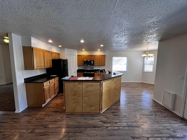 kitchen featuring dark wood-style flooring, a center island with sink, dark countertops, visible vents, and appliances with stainless steel finishes