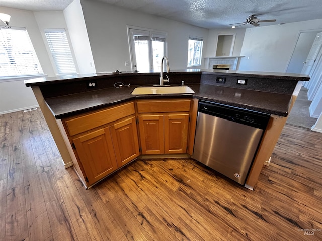 kitchen featuring dark countertops, dishwasher, a textured ceiling, and a sink