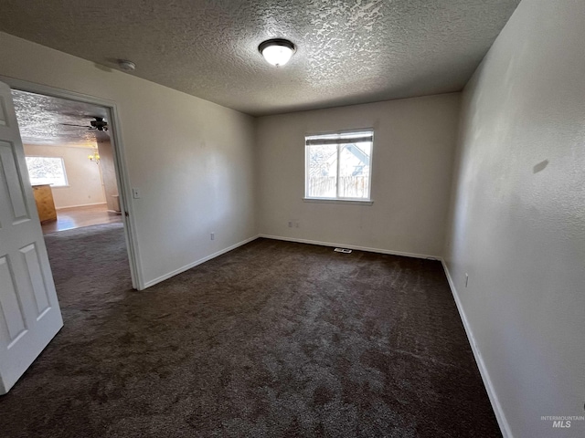 carpeted spare room with a textured ceiling and baseboards