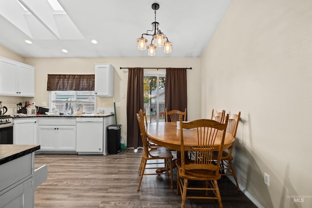 dining room with hardwood / wood-style flooring, a chandelier, sink, and a skylight