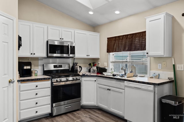 kitchen featuring dark hardwood / wood-style floors, white cabinetry, stainless steel appliances, and vaulted ceiling