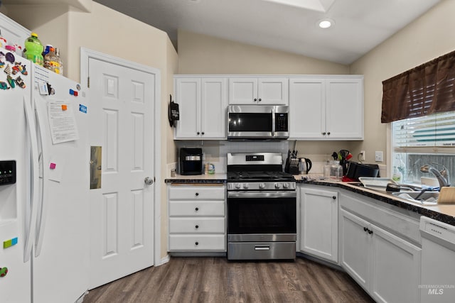 kitchen with dark wood-type flooring, backsplash, vaulted ceiling, white cabinetry, and appliances with stainless steel finishes