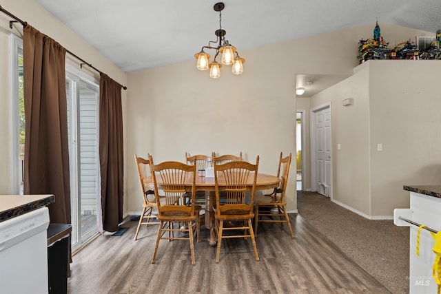 dining space with lofted ceiling, hardwood / wood-style floors, and a notable chandelier