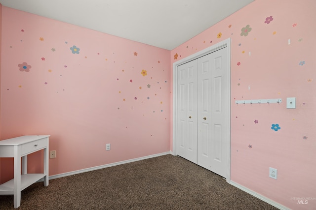 unfurnished bedroom with a closet and dark carpet