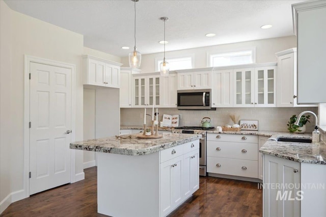 kitchen featuring a sink, appliances with stainless steel finishes, backsplash, and dark wood finished floors