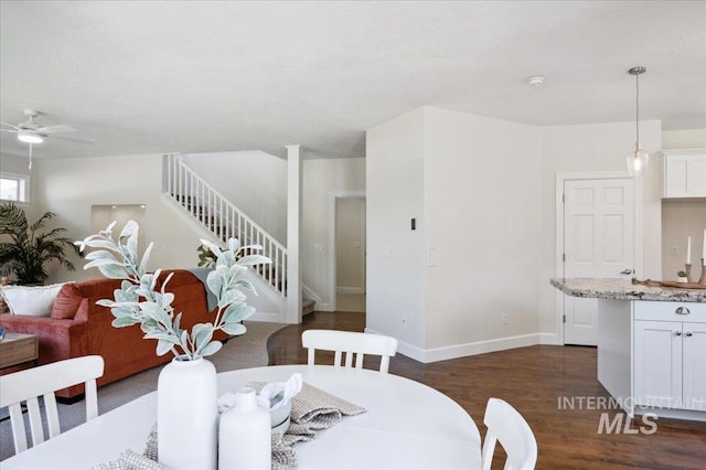 dining space featuring stairway, baseboards, a ceiling fan, and dark wood finished floors