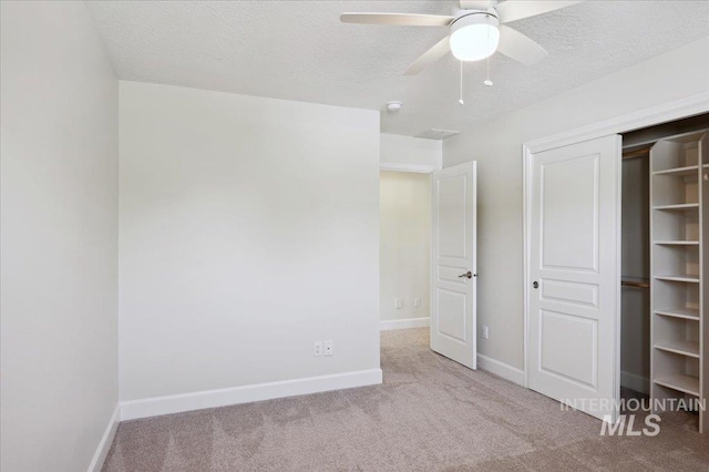 unfurnished bedroom featuring carpet floors, a textured ceiling, baseboards, and a closet