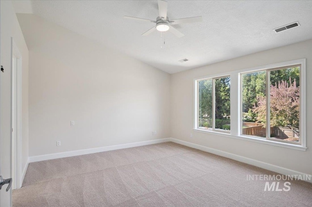 empty room featuring visible vents, light carpet, baseboards, ceiling fan, and a textured ceiling