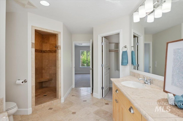 bathroom featuring baseboards, tile patterned floors, vanity, and tiled shower