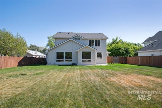 rear view of house featuring a fenced backyard and a yard