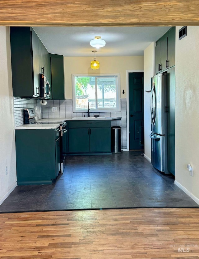 23212NDAVEN 2nd Ave N, Lewiston, ID 83501 - kitchen with green cabinetry, dark wood-type flooring, baseboards, appliances with stainless steel finishes, and decorative backsplash