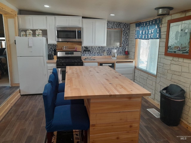 kitchen featuring stainless steel appliances, vaulted ceiling, wooden counters, white cabinets, and dark hardwood / wood-style floors