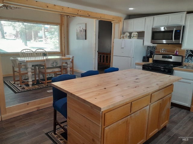 kitchen with dark hardwood / wood-style flooring, white cabinets, range with gas stovetop, and white fridge