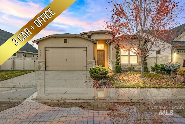 4595 N Tirso Ave, Meridian, ID 83646 - view of front of house with fence, stone siding, stucco siding, an attached garage, and driveway