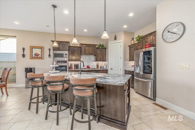 4595 N Tirso Ave, Meridian, ID 83646 - kitchen with decorative backsplash, dark brown cabinetry, light stone countertops, a sink, and stainless steel appliances