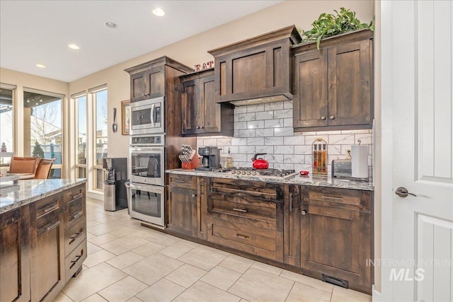 4595 N Tirso Ave, Meridian, ID 83646 - kitchen featuring dark brown cabinetry, recessed lighting, light stone counters, appliances with stainless steel finishes, and backsplash