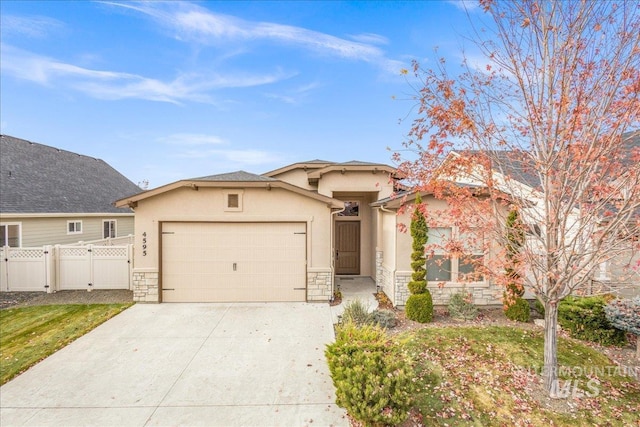 4595 N Tirso Ave, Meridian, ID 83646 - view of front facade with driveway, a gate, an attached garage, stone siding, and stucco siding
