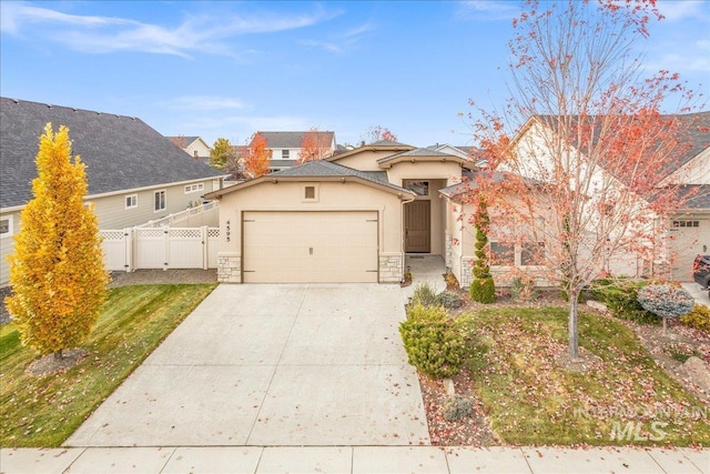 4595 N Tirso Ave, Meridian, ID 83646 - view of front of house featuring fence, an attached garage, stone siding, stucco siding, and driveway
