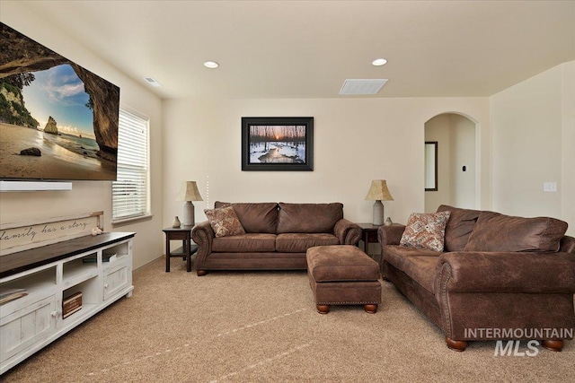 living room with visible vents, recessed lighting, arched walkways, and light carpet